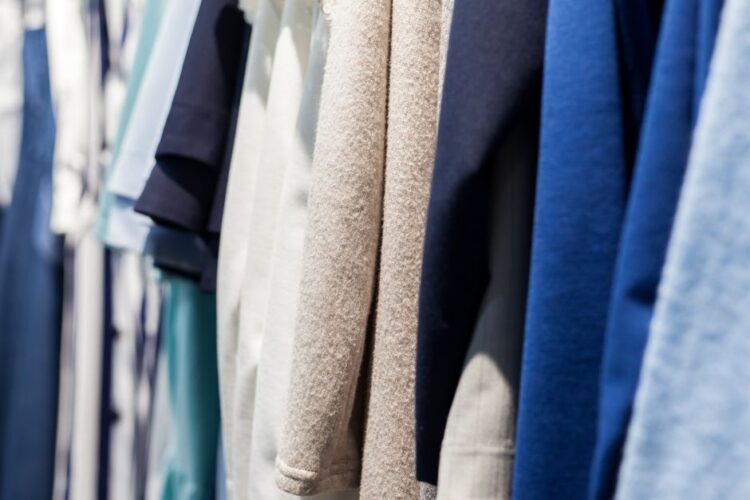 Collection of wear made of natural fabrics and hanging in shop with shiny light on blurred background