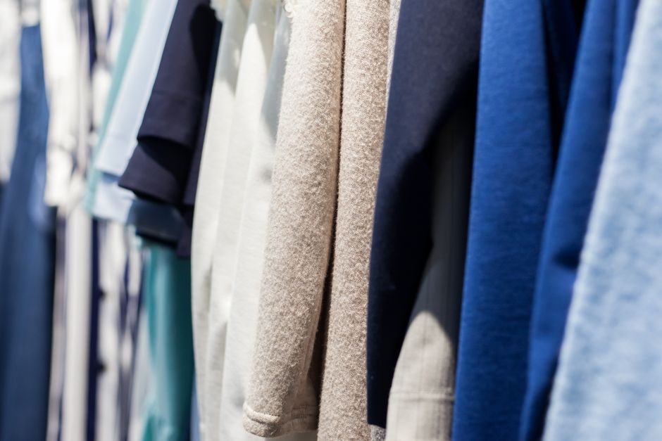 Collection of wear made of natural fabrics and hanging in shop with shiny light on blurred background