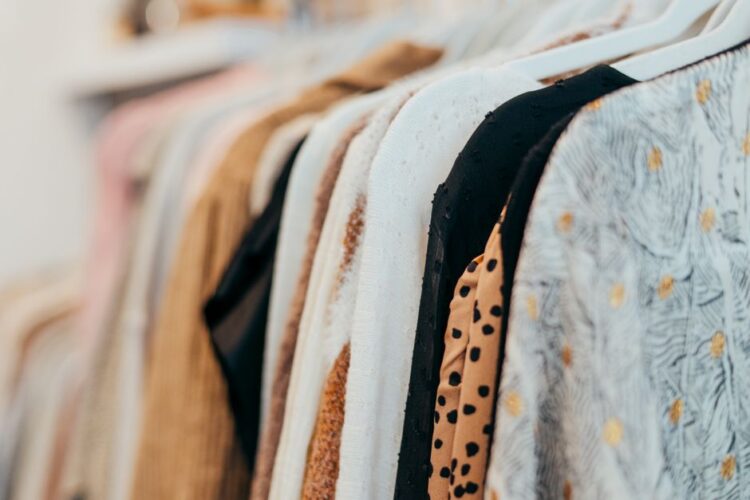 A close-up view of fashionable clothes hanging on racks in a boutique setting, showcasing various patterns and textures.