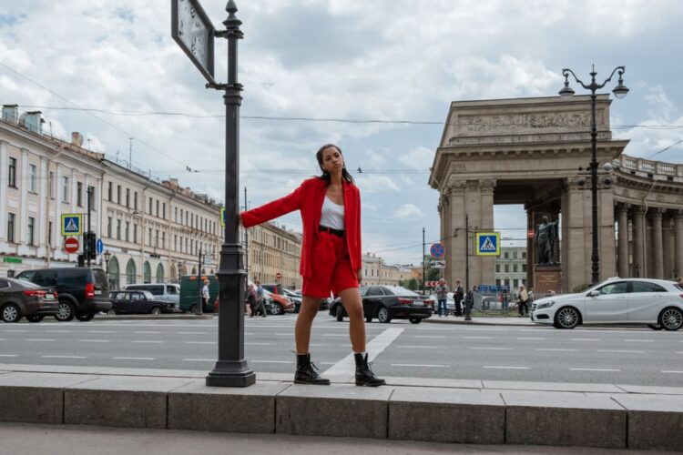 Stylish woman in red suit poses on Nevsky Prospekt with Saint Petersburg architecture.