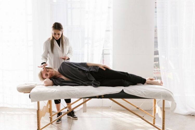 Young woman therapist provides relaxing massage therapy to a male client indoors.